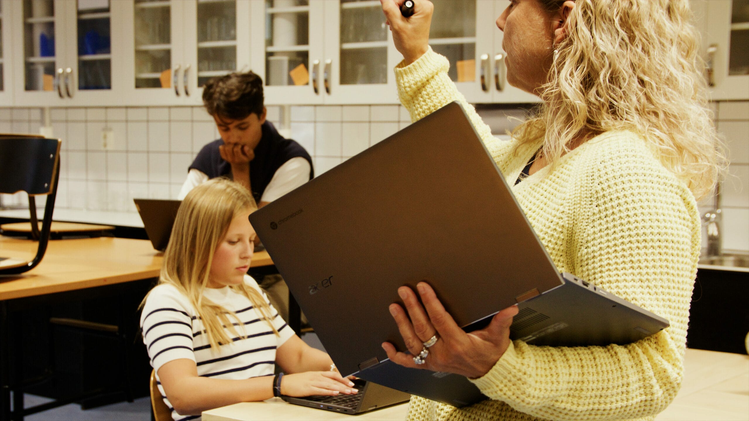 Acer Chromebook being held by blonde teacher in the middle of the classroom